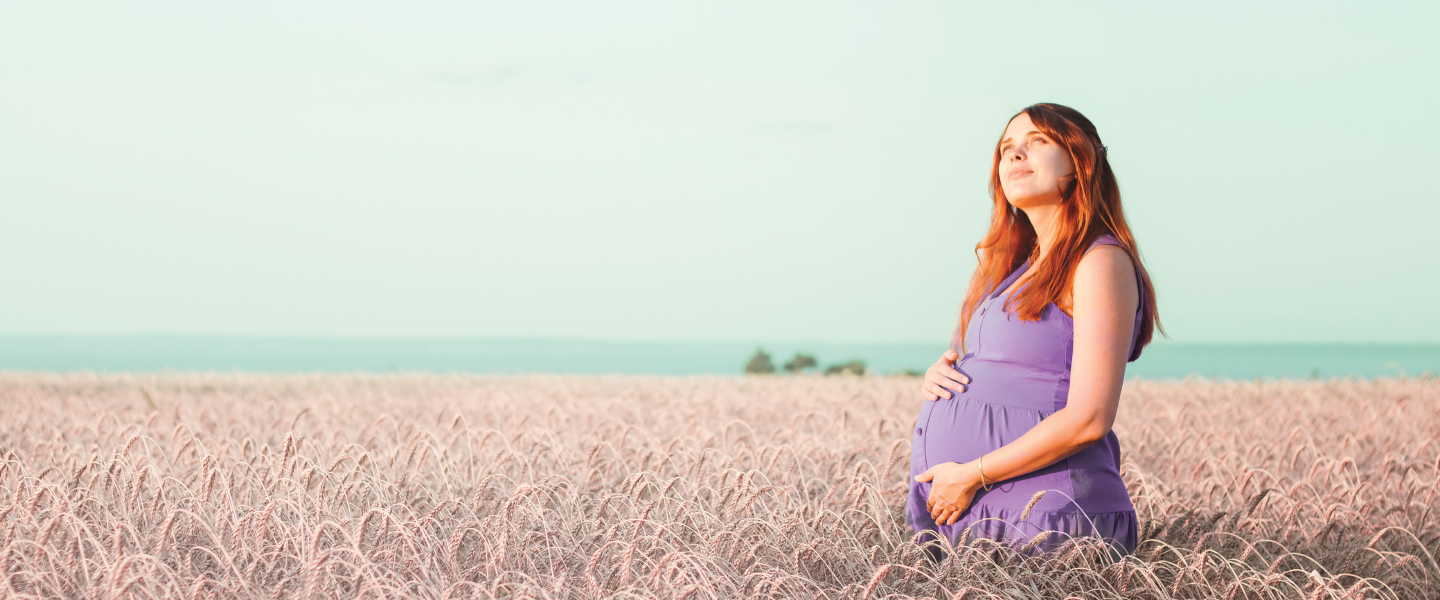 Photograph of pregnant woman  standing in a field.